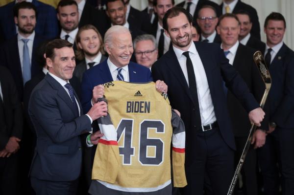 Biden posing with a hockey sweater presented to him by the Stanley Cup champions.
