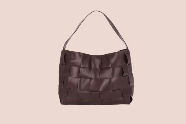 Genesis Rodriguez holding a brown woven bag with a handle