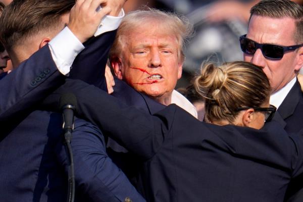 Former President Do<em></em>nald Trump being assisted off the stage by Secret Service agents at a campaign event in Butler, Pennsylvania, in 2024