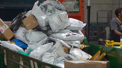 A large pile of a<em></em>bout 50 packages being dumped on a co<em></em>nveyor belt