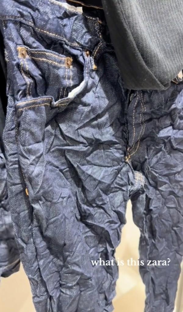 TRF creased-effect mid-rise jeans with dark-wash denim, 5 pockets and a me<em></em>tal button fastening laying on a white background.