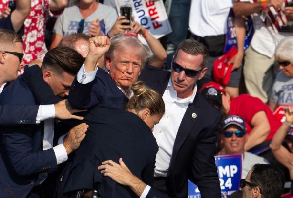 o<em></em>nald Trump is seen with blood on his face surrounded by secret service agents as he is taken off the stage at a campaign event.