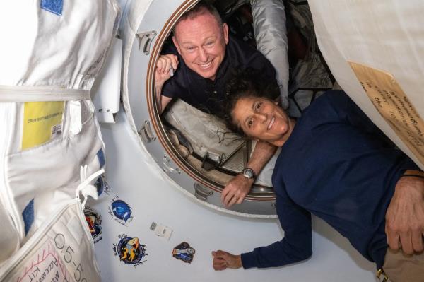 Astro<em></em>nauts Butch Wilmore and Suni Williams smiling inside the NASA's Boeing Starliner spacecraft.