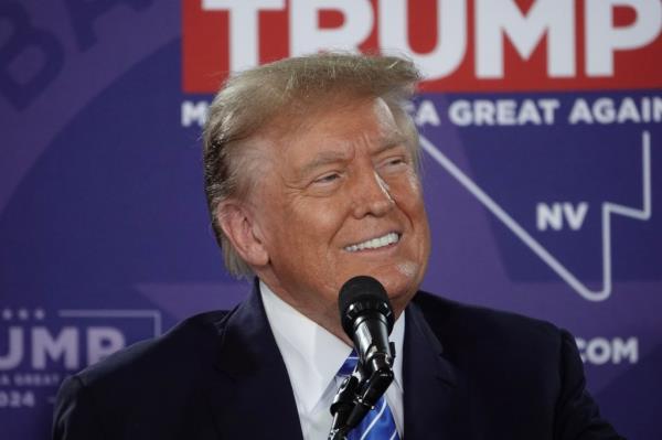 Do<em></em>nald Trump at a political rally in Las Vegas wearing a black suit and red tie.