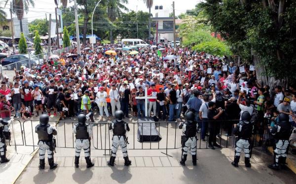 Migrants take to the streets of Tapachula inside a blocked-off area as police officers look on, during a demo<em></em>nstration on Oct. 26, 2023.
