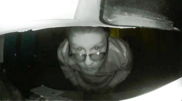 hartman in glasses peering into a hidden camera as he sets it up