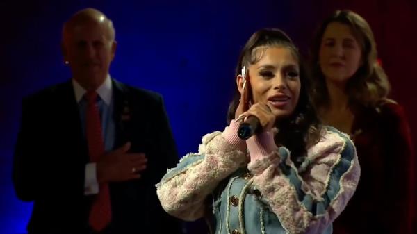 Indie singer Loomis holding a microphone at the third-party presidential debate, a<em></em>bout to sing the Star-Spangled Banner
