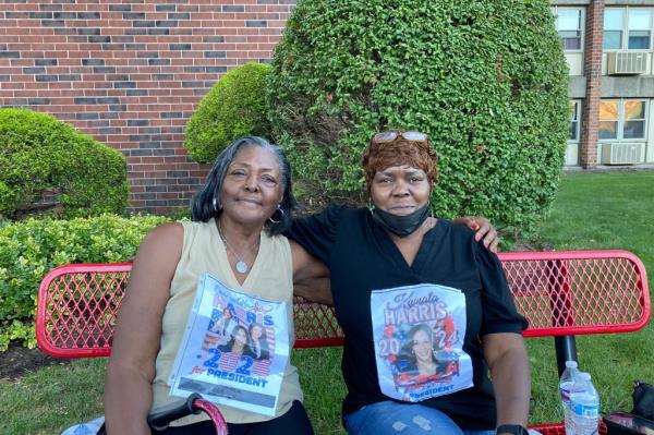 Phyllis Champine silently protesting at a Trump rally in Johnstown, seated on a bench with a picture of Kamala Harris on her blouse.