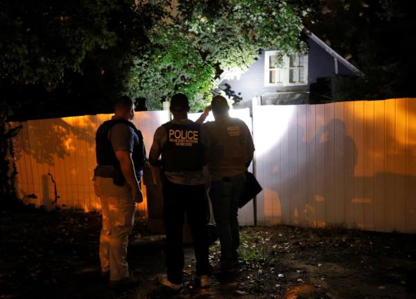 Law enforcement officers shining a flashlight near the house's fence during the raid.