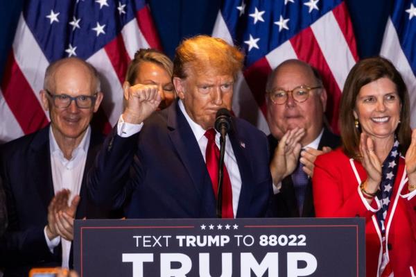 Do<em></em>nald Trump gestures triumphantly after winning Republican primary in South Carolina, surrounded by supporters and press.