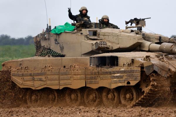 An Israeli soldier gestures to the camera as he rides alo<em></em>ngside another soldier in a tank near the Israel-Gaza border
