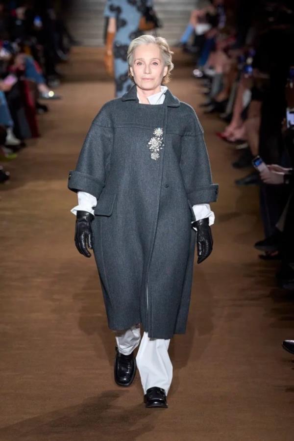 Kristin Scott Thomas walking down the Miu Miu runway in outerwear adorned with a cluster of crystal brooches