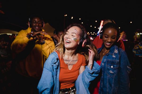 Young woman dancing with friends at silent disco at night.