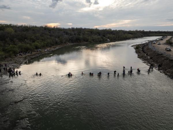 Migrants cross a river