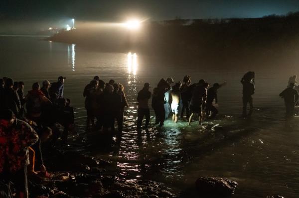 Migrants cross a river. 