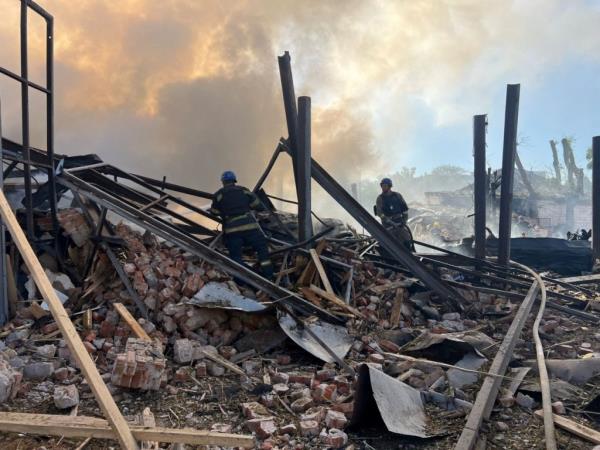 A photo of damage from a Russian missile strike shows two people walking through a pile of rubble.