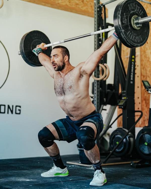 Dukic is shirtless in the gym while lifting weights