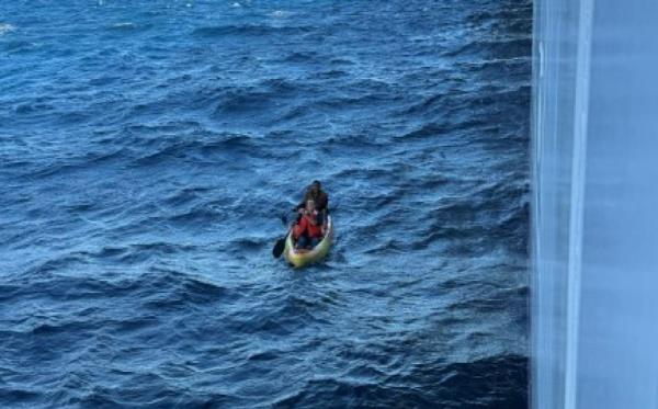 Two men paddle in a kayak in the ocean. 