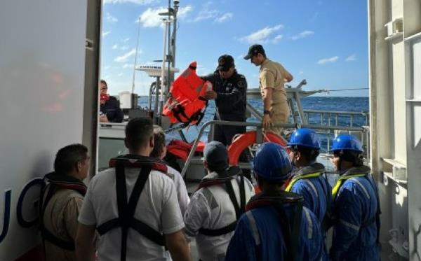 Crew members look out the door as a ship pulls up. 