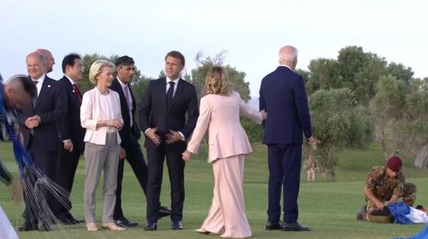 President Joe Biden wandering while world leaders including Emmanuel Macron, Ursula von der Leyen, Olaf Scholz, Fumio Kishida, Rishi Sunak watch a parachute drop at G7 summit