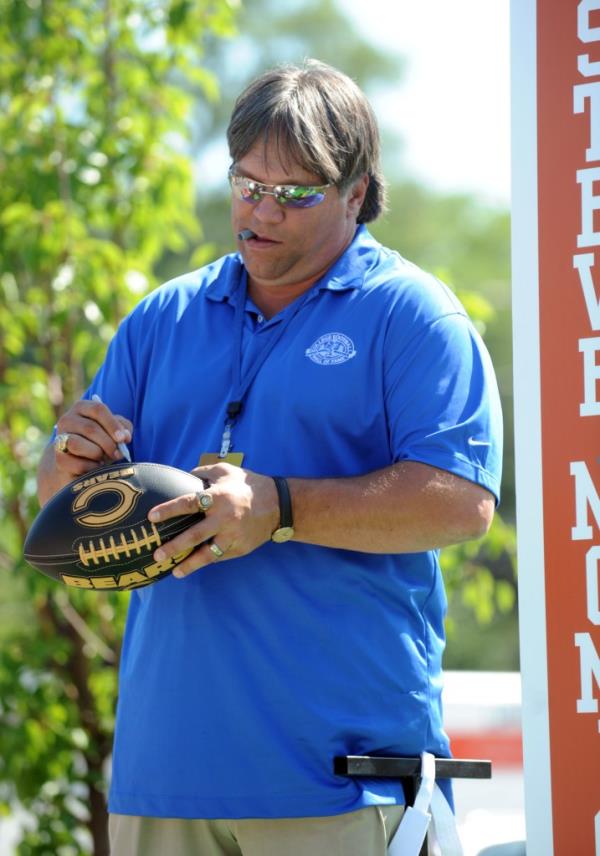 Steve McMichael, defensive tackle Texas 1976-1979, autographs a football as he stands on the float at the parade during the Hall Enshrinement Festival Saturday July 17, 2010 in South Bend, Ind.
