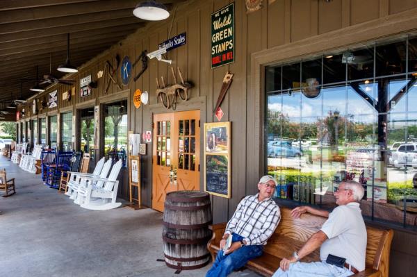 Two senior men sitting on rainbow colored rocking chairs outside Cracker Barrel Old Country Store