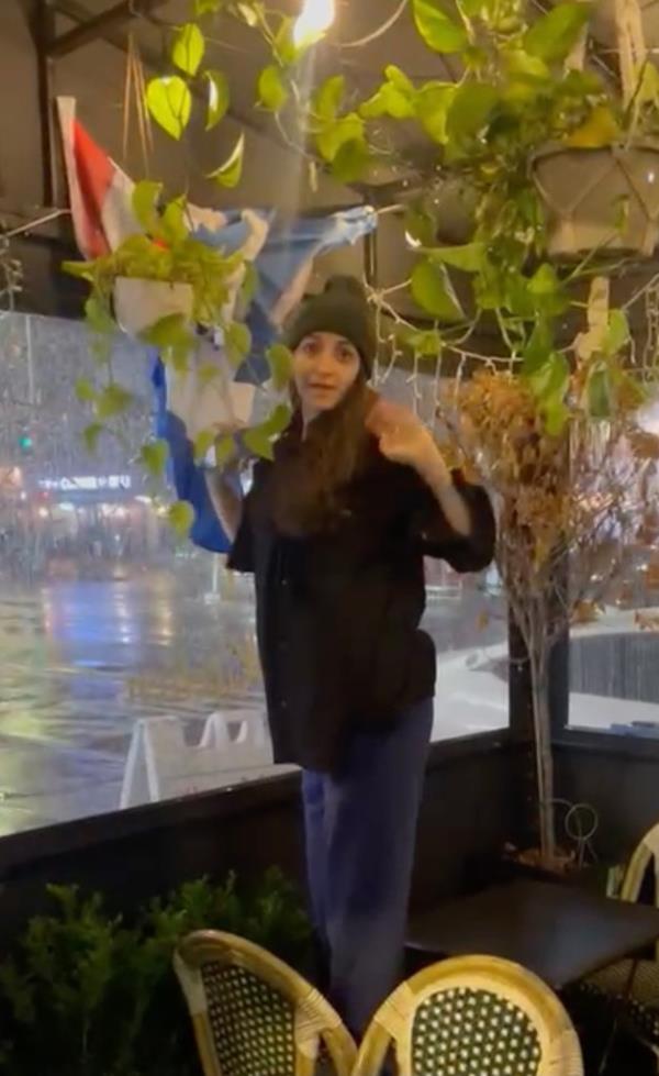 The woman steps on a restaurant chair and attempts to cover an Israel/US flag, according to surveillance footage.
