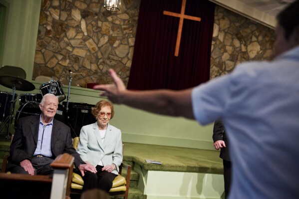 Former President Jimmy Carter, left, sits with his wife, Rosalynn, as they wait to pose for photos after Carter taught Sunday School class at Maranatha Baptist Church in his hometown of Plains, Ga., Sunday, Aug. 23, 2015. (AP Photo/David Goldman)