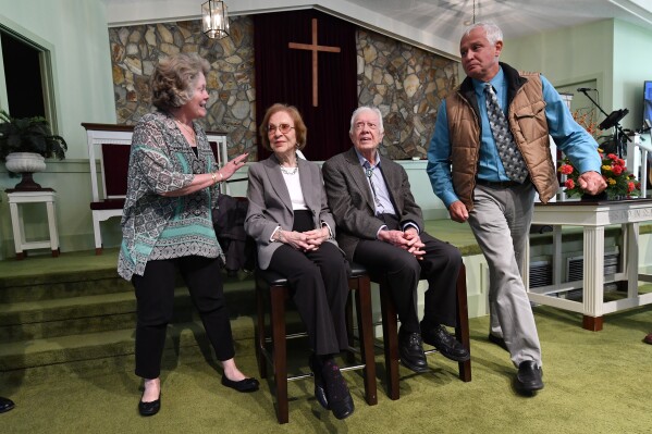 Former President Jimmy Carter, left, sits with his wife Rosalynn as they pose for photos with Bill Bush, of Adel, Ga., from right, his grandson Carson Shirley, 9, daughter Lara Norris, and wife Pat Bush after Carter taught Sunday School class at Maranatha Baptist Church in his hometown Sunday, Aug. 23, 2015, in Plains, Ga. (AP Photo/David Goldman)