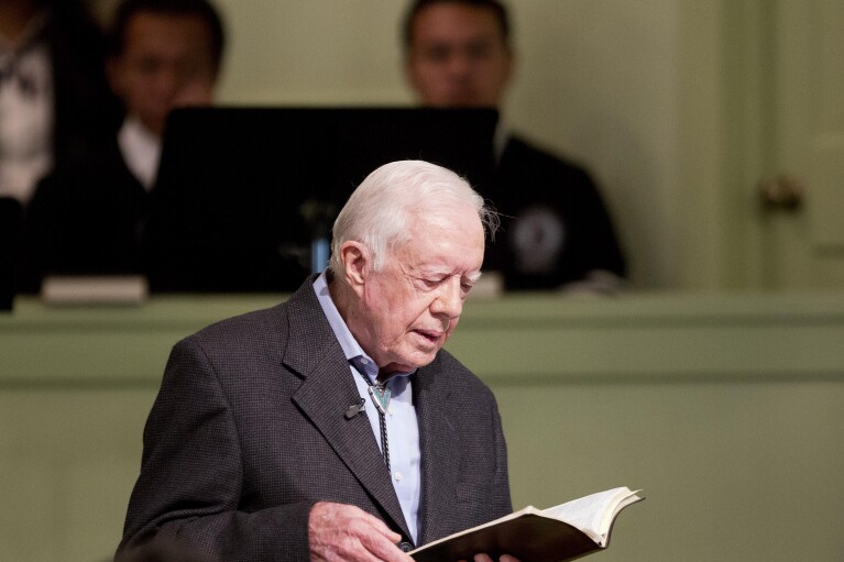 Former President Jimmy Carter opens up a Bible while teaching Sunday School class at the Maranatha Baptist Church in his hometown Sunday, Aug. 23, 2015, in Plains, Ga. (AP Photo/David Goldman)